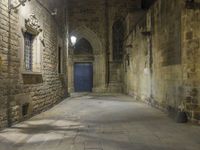 an old stone walkway in front of a doorway with blue door and brick walls leading into a room with tall windows