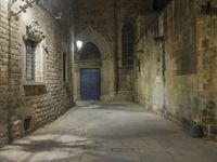 an old stone walkway in front of a doorway with blue door and brick walls leading into a room with tall windows