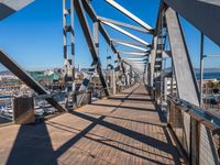 a man walks across a long bridge next to boats in a harbor, and the view of the harbor is really incredible