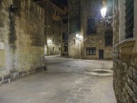 a cobbled floor area in an old town at night with light fixtures and building lights