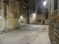 a cobbled floor area in an old town at night with light fixtures and building lights