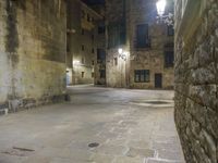 a cobbled floor area in an old town at night with light fixtures and building lights