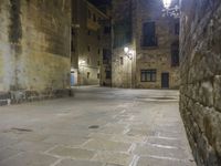 a cobbled floor area in an old town at night with light fixtures and building lights