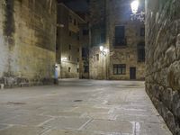 a cobbled floor area in an old town at night with light fixtures and building lights