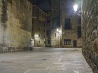 a cobbled floor area in an old town at night with light fixtures and building lights