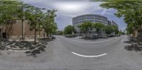 a wide angle panoramic view of an empty street and trees in the foreground