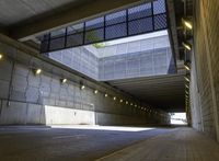 empty parking tunnel at an airport with brick walkway and low lighting on walkways, with skylights, stone walls, glass bale windows and metal grates