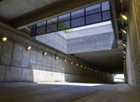 empty parking tunnel at an airport with brick walkway and low lighting on walkways, with skylights, stone walls, glass bale windows and metal grates