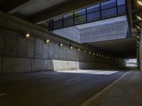 empty parking tunnel at an airport with brick walkway and low lighting on walkways, with skylights, stone walls, glass bale windows and metal grates