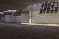 a building with a concrete wall and graffiti on it's side, next to dirt