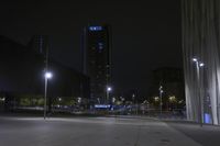 view at night of a city street with illuminated tall buildings and lights illuminating the buildings