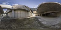 the four arches of a concrete building in a surreal way, with a man standing on top of it