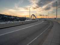 the bridge goes over the hill side and is under a dramatic sky at sunset time