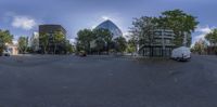 a fisheye view of a street with multiple buildings on both sides of it and trees in the foreground