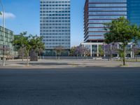 an empty street in front of a building and trees on the other side of the road