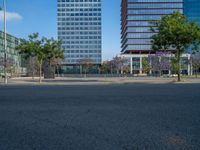 an empty street in front of a building and trees on the other side of the road