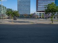 an empty street in front of a building and trees on the other side of the road