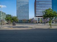 an empty street in front of a building and trees on the other side of the road