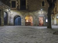 an empty cobble stone area with furniture and tables in the background at night time