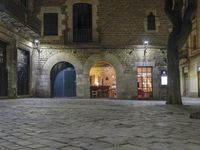 an empty cobble stone area with furniture and tables in the background at night time