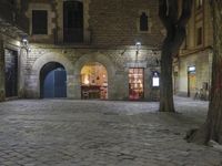 an empty cobble stone area with furniture and tables in the background at night time