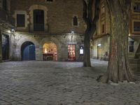 an empty cobble stone area with furniture and tables in the background at night time