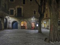 an empty cobble stone area with furniture and tables in the background at night time