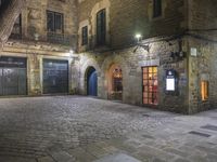 an old building at night with two doors and some windows on it's sides