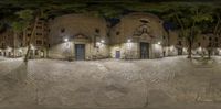 a fisheye view of an alley and a stone building at night with streetlights