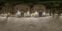 a fisheye view of an alley and a stone building at night with streetlights