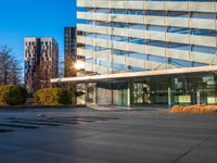 a building and its reflection in the glass on the pavement of a street with trees