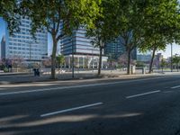 an empty street in front of a building and trees on the other side of the road