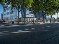 an empty street in front of a building and trees on the other side of the road