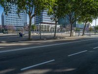 an empty street in front of a building and trees on the other side of the road