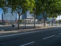 an empty street in front of a building and trees on the other side of the road