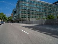 a deserted urban street with some very tall buildings behind it next to cars and a building