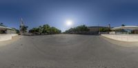 a fish eye view of a sun setting over an empty street while a person holds onto skateboard