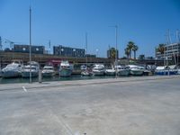 boats docked at an outdoor marina near other boats in the water with buildings and tall buildings in the background