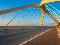 the bridge has a few light streaks on it as it crosses the street towards the road