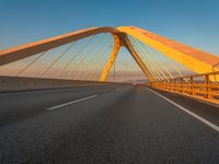 a road over an bridge and some buildings at sunset in the background on a blue sky day