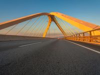 a road over an bridge and some buildings at sunset in the background on a blue sky day