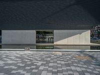 a white building next to a pool in a courtyard area with a walkway leading into it