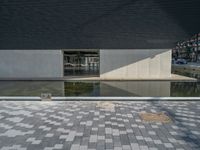 a white building next to a pool in a courtyard area with a walkway leading into it