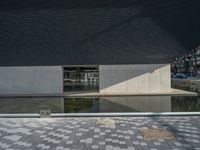 a white building next to a pool in a courtyard area with a walkway leading into it