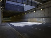 an empty parking lot with light on, and concrete and glass buildings around it and pavement