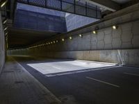 an empty parking lot with light on, and concrete and glass buildings around it and pavement