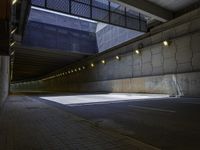 an empty parking lot with light on, and concrete and glass buildings around it and pavement