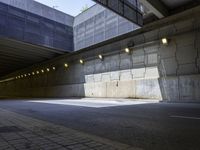 the asphalt road underpass of an empty concrete wall near many lights and buildings, some lighting turned on