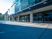 this is an empty street near a modern building with glass windows on the sides and a metal frame on top of the building