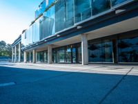 this is an empty street near a modern building with glass windows on the sides and a metal frame on top of the building